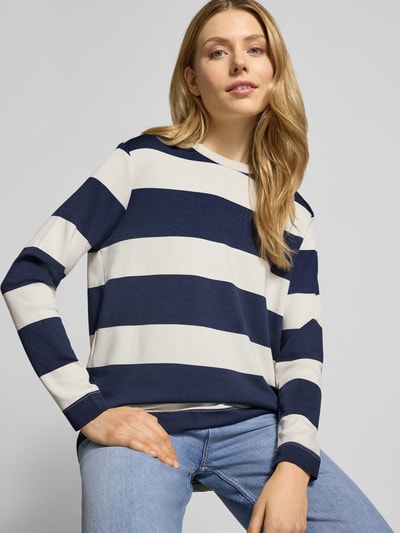 Modelka kobieca nosi Sweatshirt mit geripptem Rundhalsausschnitt Modell 'BARNI' od Soyaconcept, mieszanka materiałów z domieszką modalu, krój regular fit, wzór w szerokie granatowe i białe pasy, widoczne faktury dzianiny, widok na górną część ciała z przodu.