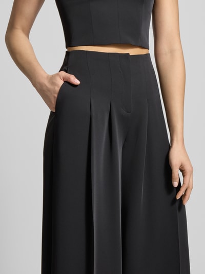 Frauenmodel trägt Stoffhose mit weitem Bein und gelegten Falten von Jake*s Cocktail, Schwarz, Material-Mix mit Stretch, Nahaufnahme Oberkörper.
