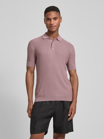 Männermodel trägt Slim Fit Poloshirt aus Viskose-Mix von Antony Morato in Strick-Optik, rosa, Polokragen, Kurzärmelig, Ganzkörperansicht von vorne.