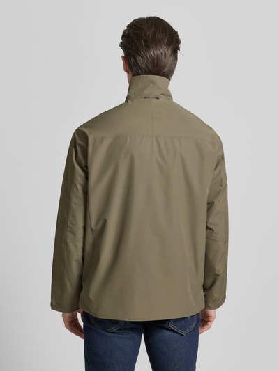 Männermodel trägt olivgrüne Softshell-Jacke mit Label-Details von PEAK PERFORMANCE, gerade geschnitten, glatte Textur, Ganzkörperansicht Rückansicht.