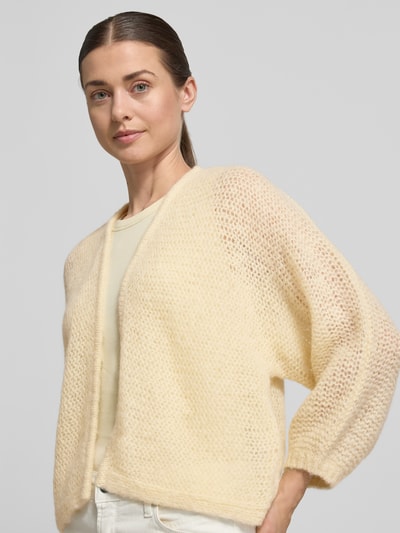 Frauenmodel trägt Relaxed Fit Cardigan mit Baby-Alpaka-Anteil Modell 'Tulea' von Someday, Strick-Optik, Material-Mix, helles Gelb, Nahaufnahme Oberkörper. Rückenlänge bei Größe 36: 51 cm, Ärmellänge 49 cm.
