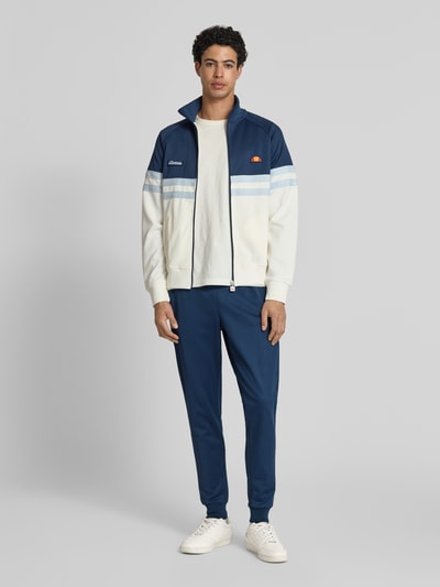 Männermodel trägt Sweatpants mit elastischem Bund Modell 'BERTONI' von Ellesse aus Baumwoll-Mix in Dunkelblau, Regular-Fit, Ganzkörperansicht von vorne.
