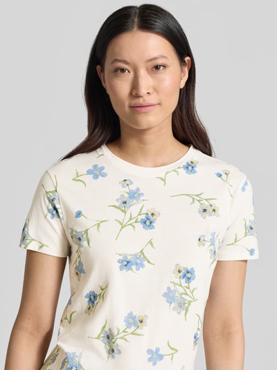 Frauenmodel trägt T-Shirt im Allover-Look mit Rundhalsausschnitt von Jake*s Casual aus reiner Baumwolle im Regular-Fit, cremefarben mit blau-grünem Blumenmuster, Rückenlänge in Größe S: 59 cm, Nahaufnahme Oberkörper.