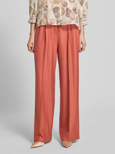 Frauenmodel trägt Wide Fit Hose aus Viskose-Elasthan-Mix von Marc Cain, Farbe Koralle, High-Waist, Bügelfalten, Ganzkörperansicht von vorne.