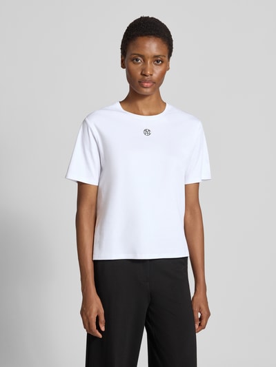 Kobiece model nosi Damski t-shirt Regular Fit T-Shirt aus reiner Baumwolle Model 'Melea' od MSCH Copenhagen, biały, nadruk z logo, okrągły dekolt, Długość tyłu w rozmiarze XS/S: 57 cm, widok całej sylwetki z przodu.