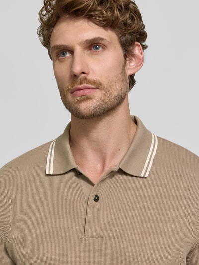 Männermodel trägt Regular Fit Poloshirt aus Baumwoll-Mix Modell 'H-Pittman 10' von BOSS in Beige mit feiner Struktur, Nahaufnahme Oberkörper. Herren Poloshirt von BOSS.