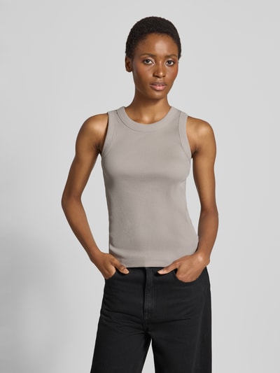 Kobiece modelka nosi Skinny Fit Tanktop aus reiner Baumwolle von DRYKORN w szarym kolorze, efekt prążkowania, okrągły dekolt, długość tyłu w rozmiarze S: 54 cm, widok na cały przód sylwetki.