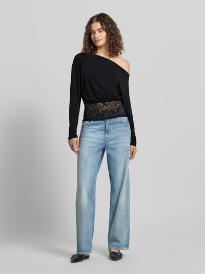 Vrouwenmodel draagt Longsleeve met asymmetrische hals model 'Mirelin' van Gina Tricot, materiaalmix met stretch, nauwsluitend model, kant. Ganzlichaamsaanzicht van voren.