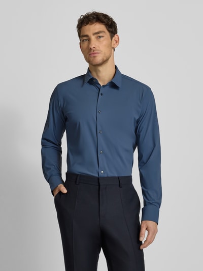 Männermodel draagt Regular Fit zakelijk overhemd uit ademend materiaal Model 'JOE' van BOSS in effen kleur, Kentkraag, doorlopende knoopsluiting, achterpas, lange mouwen met verstelbare manchet, afgeronde rompzoom, stretch, vochtregulerend. Ganzkörperansicht van voren.