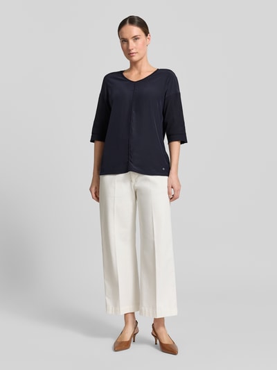 Frauenmodel trägt T-Shirt mit Ärmelaufschlag und Rundhalsausschnitt von Marc Cain, Baumwoll-Mix mit Stretch-Anteil, Straight Fit, Label-Detail, Rückenlänge bei Größe 36: 62 cm, dunkelblau, glatte Textur, Ganzkörperansicht von vorne.