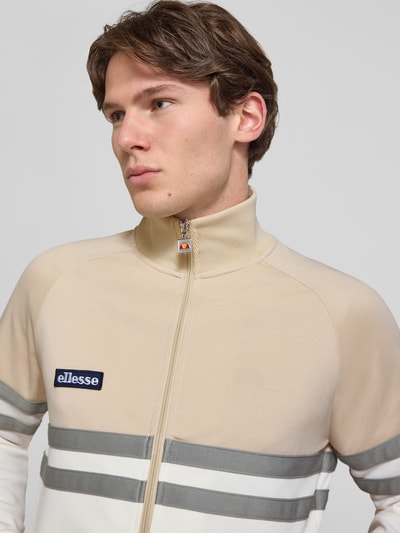 Männermodel trägt Trainingsjacke mit Label-Patch und Stehkragen Modell 'RIMINI' von ellesse aus Baumwoll-Mix, Nahaufnahme Oberkörper.
