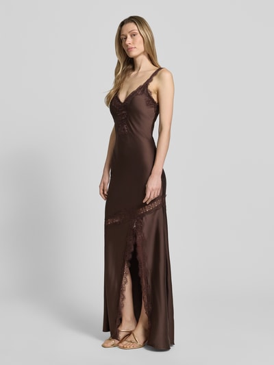 Modelka nosi długa sukienka Maxikleid mit Spitzenbesatz und Gehschlitz von Little Mistress, mieszanka materiałów z dodatkiem streczu, podkreślająca figurę, obszycie koronką, dekolt w serek, rozporek, długość tyłu w rozmiarze 36: 151 cm, szerokość w rozmiarze 36: 31 cm, brązowy odcień, widoczne miękkie tekstury, gładka powierzchnia, całkowity widok z przodu.
