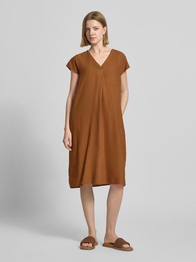 Frauenmodel trägt knielanges Leinenkleid mit V-Ausschnitt Modell 'Ina' von Soyaconcept, Leinen-Mix mit Viskose-Anteil, Loose-Fit, Seitliche Schlitze, einfarbig braun, glatte Textur, Ganzkörperansicht von vorne.