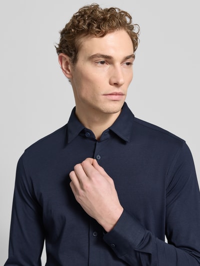 Männermodel trägt Slim Fit Businesshemd mit Stretch-Anteil von BOSS, dunkelblau, Kentkragen, Knopfleiste, Nahaufnahme Oberkörper.