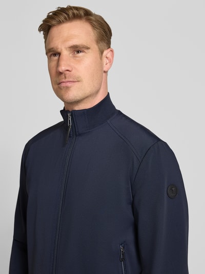 Mężczyznamodel nosi kurtkę z mieszanki materiałów z dodatkiem streczu, krój regular fit, model 'Pablo' od JOOP! Collection, stójka, kieszenie zapinane na zamek błyskawiczny, kolor granatowy, tekstura drobno fakturowana, długość tyłu w rozmiarze 50: 66 cm, szerokość ramion w rozmiarze 50: 45 cm, szerokość klatki piersiowej w rozmiarze 50: 56 cm, długość rękawów w rozmiarze 50: 65 cm, zbliżenie na górną część ciała, widok z przodu.