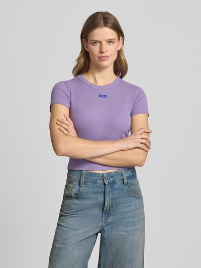 Kobiece modelka ma na sobie damski t-shirt Slim Fit T-Shirt aus Baumwoll-Mix Modell 'Baby Tee' od Hugo Blue, efekt: jednolity kolor, krój slim fit, długość: krój krótki, detal z logo, okrągły dekolt, rękaw: krótki rękaw, wykończenie materiału: dżersej, materiał: mieszanka bawełny; widok całej sylwetki z przodu.