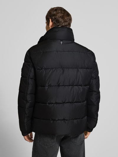 Männermodel trägt schwarze Regular Fit Steppjacke mit Logo-Detail Modell 'Newton' von JOOP!, Herren Bomberjacke, Ganzkörperansicht Rückansicht.