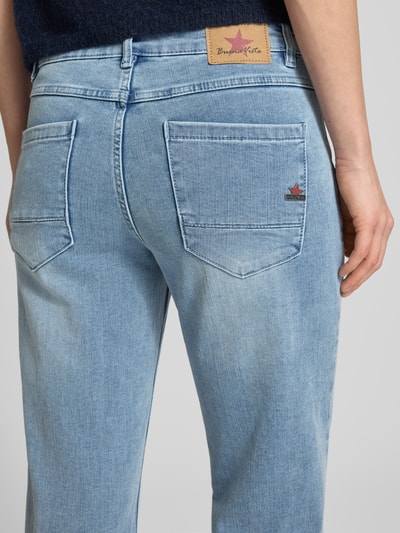 Frauenmodel trägt Straight Fit Jeans mit Viskose-Anteil Modell 'Anna' von Buena Vista in hellblau mit Gesäßtaschen, Detailaufnahme Rückansicht, elastischer Baumwoll-Mix, sichtbares Markenlogo auf Lederpatch.