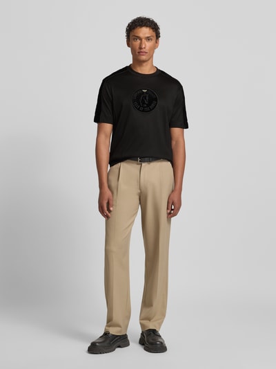 Männermodel trägt T-Shirt mit Label-Detail von Emporio Armani in Schwarz, Lyocell-Baumwoll-Mix, Regular-Fit, Rundhalsausschnitt, Ganzkörperansicht von vorne