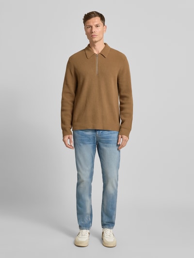 Männermodel trägt Slim Fit Jeans aus Baumwoll-Mix Modell 'DELAWARE BO' von BOSS Orange in Denim-Optik, Ganzkörperansicht von vorne.