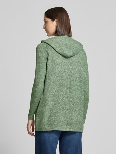 Frauenmodel trägt Regular Fit Cardigan mit Kapuze Modell 'DOFFY' von VERO MODA in meliertem Grün, strukturierte Oberfläche, Ganzkörperansicht Rückansicht.