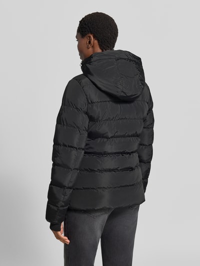 Männermodel trägt czarna kurtka z efektem pikowania Regular fit Modell 'Synria' od Cars Jeans z kapturem, wpuszczane kieszenie, zamek błyskawiczny, Długość tyłu w rozmiarze S: 65 cm, szerokość ramion w rozmiarze S: 42 cm, szerokość klatki piersiowej w rozmiarze S: 50 cm, długość rękawów w rozmiarze S: 70 cm, widok całej sylwetki z tyłu.