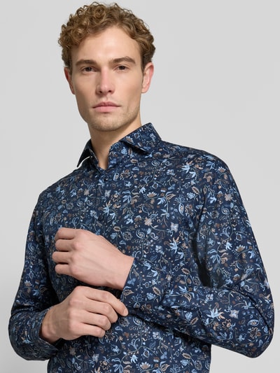 Männermodel trägt Regular Fit Businesshemd aus reiner Baumwolle von OLYMP mit blauem floralen Muster, Nahaufnahme Oberkörper, Herren Businesshemd von OLYMP.