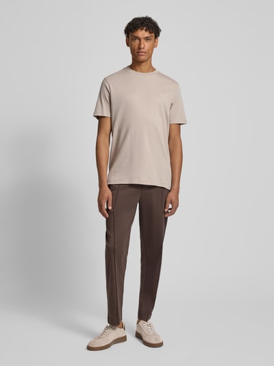 Męski model nosi T-Shirt mit Logo-Stitching Modell 'Priamo' od JOOP! Collection, jasnobeżowa bawełna, krój regular fit, okrągły dekolt, długość tyłu w rozmiarze M: 69 cm, widok całej sylwetki z przodu.