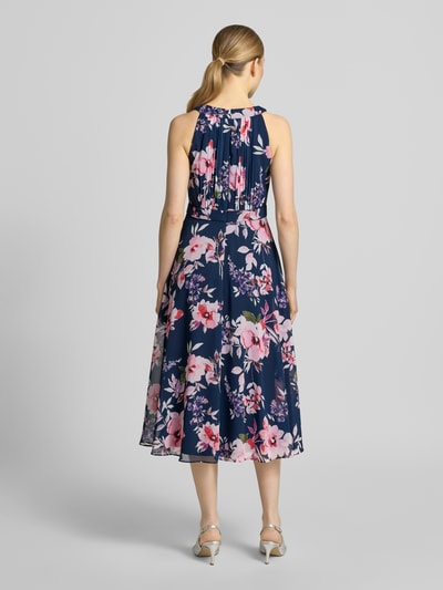 Frauenmodel trägt Midikleid mit floralem Allover-Print von Christian Berg Cocktail in Dunkelblau, Taillierte Passform, Rundhalsausschnitt, Gelegte Falten, Ärmelloses-Design, Nahtreißverschluss, Ganzkörperansicht Rückansicht.
