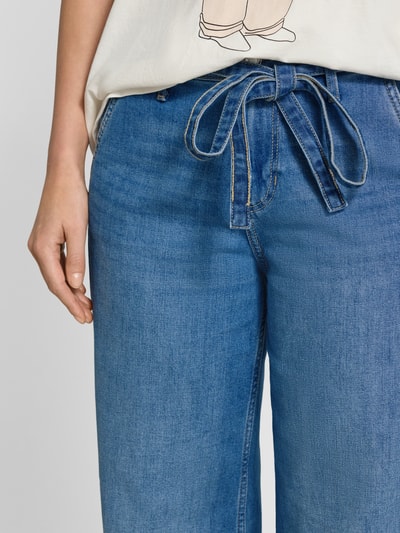 Vrouwenmodel draagt Wide Leg Jeans uit katoenmix model 'SURI' van s.Oliver RED LABEL, denimlook met ceintuur, detailopname taille.