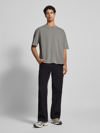 Männermodel trägt Oversized T-Shirt mit Label-Stitching von Pegador aus reiner Baumwolle mit geripptem Rundhalsausschnitt, Ganzkörperansicht von vorne.