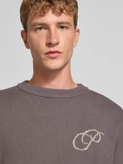 Männermodel trägt Relaxed Fit Strickpullover aus reiner katoen van PROHIBITED, labelstitching, ribboorden, kleur grijs, puur katoen textuur, Nahaufnahme Oberkörper. Ruglengte maat M: 64 cm, mouwlengte: 59 cm.