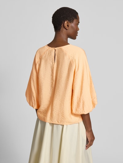 Frauenmodel trägt Regular Fit Bluse aus Viskose-Mix mit 3/4-Arm von Christian Berg Woman in Hellorange, strukturierte Textur, Ganzkörperansicht Rückansicht. Damen Bluse, Rundhalsausschnitt, Rückenlänge bei Größe 36: 56 cm, Ärmellänge bei Größe 36: 44 cm.