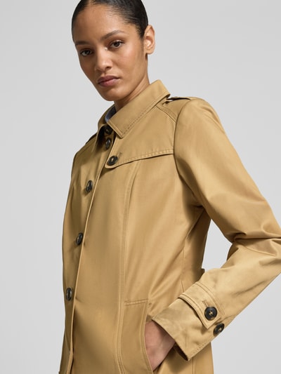 Frauenmodel trägt Trenchcoat mit Ärmelriegeln von Fuchs Schmitt in Beige, Knopfleiste, Umlegekragen, Nahaufnahme Oberkörper. Regular Fit, Eingrifftaschen, Rückenlänge 78 cm, Schulterbreite 39 cm, Brustweite 49 cm, Ärmellänge 63 cm.