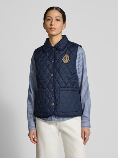 Kobiece model prezentuje Regular Fit Steppweste mit Umlegekragen von Lauren Ralph Lauren, granatowy kolor, przeszycia karo, logo-patch, metaliczne akcenty, nałożone kieszenie boczne, krój regular fit, widok całej sylwetki z przodu.