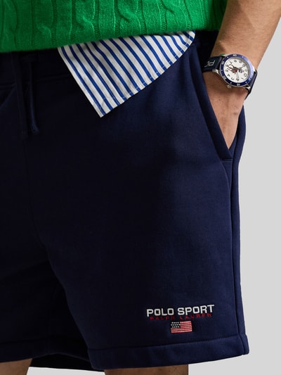 Männermodel trägt Regular Fit Sweatshorts aus Baumwoll-Mix von Polo Ralph Lauren in uni navy, elastischer Bund mit Tunnelzug, label-schriftzug, seitliche steekzakken, achterzak, sweatstof; Nahaufnahme Oberkörper.