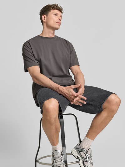 Männermodel trägt Relaxed Fit T-Shirt aus reiner Bio-Baumwolle Modell 'ICONIC MAARKOS GD' von Armedangels, unifarben, Jersey, Logo-Print, Nahaufnahme Oberkörper.