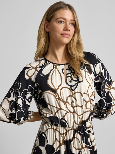 Vrouwenmodel draagt 'Midikleid aus reiner Viskose mit floralem Allover-Print' van Betty Barclay in zwart-wit-bruin, regular fit, bloemenprint, ronde hals, 3/4-mouw, plooien look, lengte rug maat 36: 125 cm, borstwijdte: 34 cm, mouwlengte: 57 cm, bovenlichaam close-up.