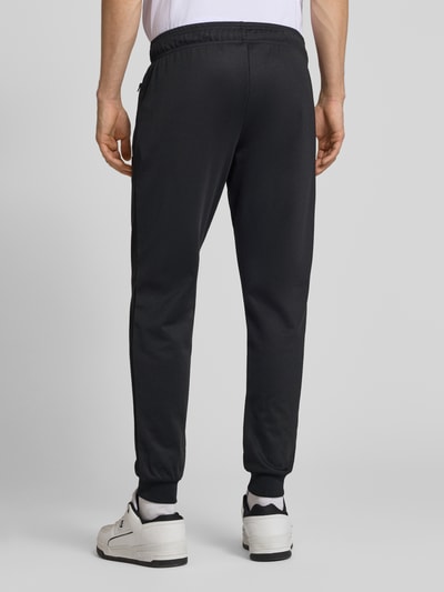 Męski model nosi Sweatpants mit elastischem Bund Modell 'BERTONI' od Ellesse z mieszanki bawełny, krój regular fit, czarne, detal z logo, długość wewnętrzna nogawki 76 cm w rozmiarze M, całkowity widok z tyłu.