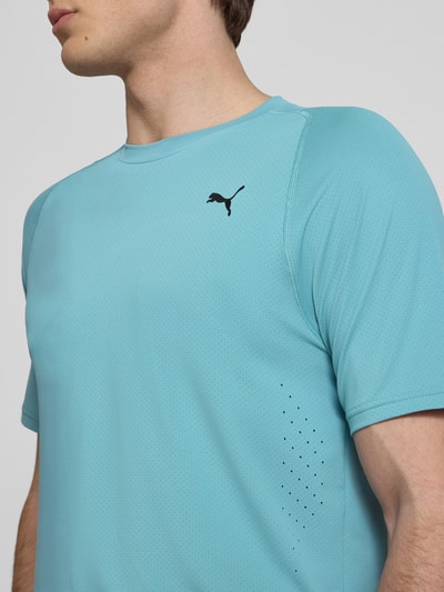 Männermodel trägt T-Shirt mit Label-Print von PUMA PERFORMANCE, hellblau, Material-Mix mit Stretch-Anteil, Regular-Fit, Nahaufnahme Oberkörper.