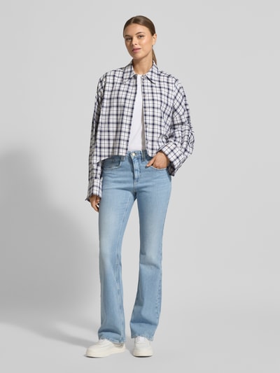 Frauenmodel trägt Flared Jeans mit Eingrifftaschen Modell 'Mary' von BRAX in hellem Blau, Knopf-Reißverschluss, Bundweite 41 cm bei Größe 36, Ganzkörperansicht von vorne.