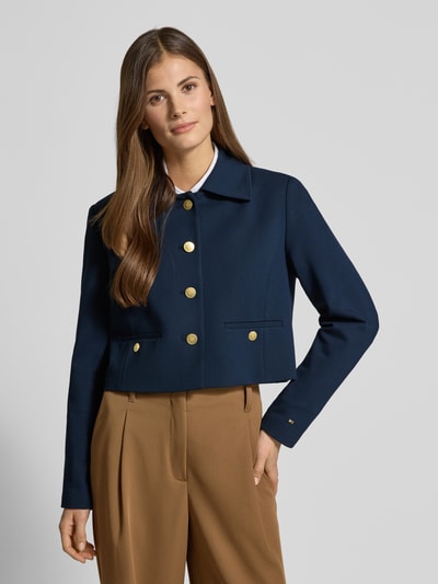Frauenmodel trägt Regular Fit Kurzblazer aus Viskose-Mix Modell 'PUNTO' von Tommy Hilfiger, Optik: Unifarben, Umlegekragen, Cropped, einreihige Knopfleiste, Logo-Applikation, Langarm mit dekorativem Knopf, Paspeltaschen, Material: Viskose-Mix, Farbkontrast Dunkelblau/Beige, glatte Textur, Ganzkörperansicht von vorne.