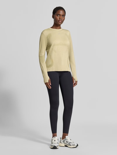 Frauenmodel trägt Slim Fit Longsleeve mit Logo-Print Modell 'Road' von ASICS TIGER in Beige, kombiniert mit dunkler Leggings, Ganzkörperansicht von vorne, Damen Longsleeve, Rundhalsausschnitt, Rückenlänge bei Größe S 61 cm.