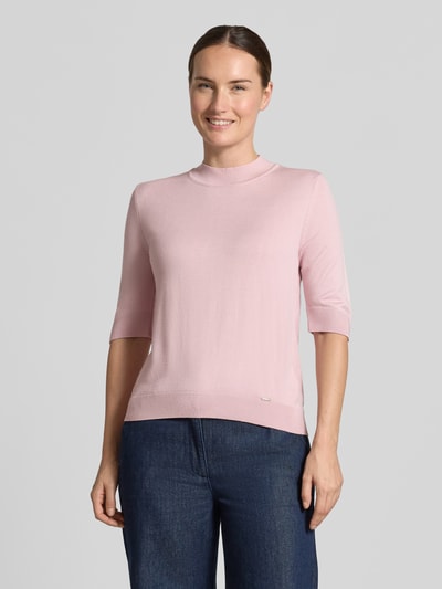 Frauenmodel trägt Strickpullover aus Viskose-Mix von MORE & MORE in Rosa mit Stehkragen, gerippten Abschlüssen und Halbarm, taillierte Passform, Ganzkörperansicht von vorne.