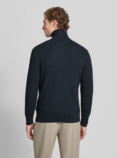 Męski model nosi czarny kardigan rozpinany z bawełny Regular Fit marki Marc O'Polo, sweter męski, widok całej sylwetki z tyłu.