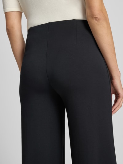 Frauenmodel trägt Wide Fit Hose mit Ziernähten von Christian Berg Woman, schwarzer elastischer Material-Mix, Nahaufnahme Rückansicht.