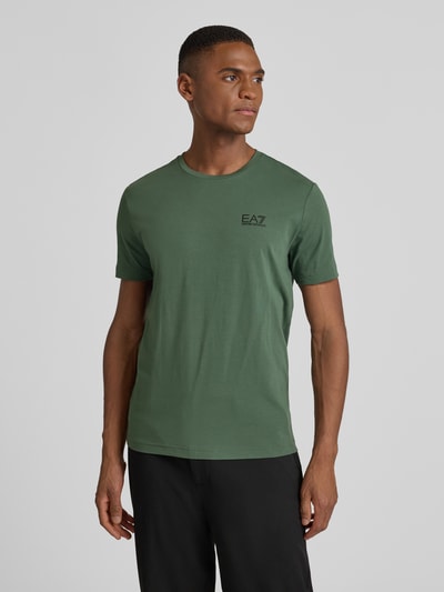 Männermodel trägt T-Shirt mit Label-Print van EA7 Emporio Armani in groen, slim fit, ronde hals, katoen-elastaan mix, Nahaufnahme Oberkörper.