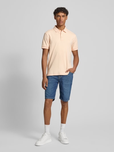 Męski model nosi bermudy im 5 kieszeni model 'Fort' od JOOP! kolekcja, mieszanka bawełny z dodatkiem streczu, krój straight fit, szerokość w rozmiarze 32: 48 cm, długość wewnętrzna nogawki: 25 cm, kolor niebieski, widok całej sylwetki z przodu.