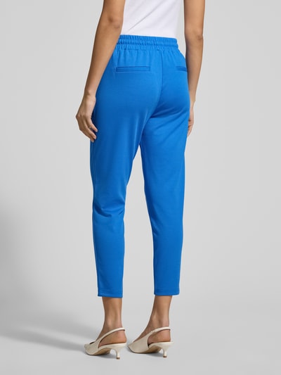 Frauenmodel trägt blaue Slim Fit Stoffhose mit Viskose-Anteil Modell 'Kate' von ICHI, elastischer Bund, Eingrifftaschen, Bundfalten, Ganzkörperansicht Rückansicht.
