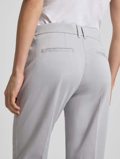Frauenmodel trägt Straight Fit Stoffhose mit Lyocell-Anteil Modell 'Mara' von Brax in Hellgrau mit Bügelfalten, Nahaufnahme Rückansicht. Elastischer Baumwoll-Mix, verkürzte Passform, Eingriff- und Gesäßtaschen, Knopf- und Reißverschluss.